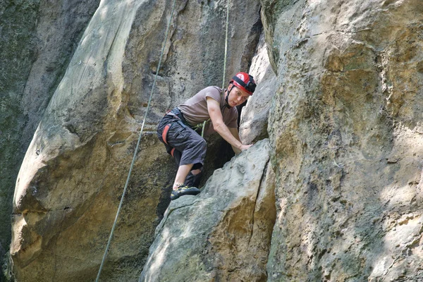 Jongeman beklimt een steile muur van rotsachtige bergen. Mannelijke klimmer overwint uitdagende route. Betrokken bij het concept extreme sport — Stockfoto