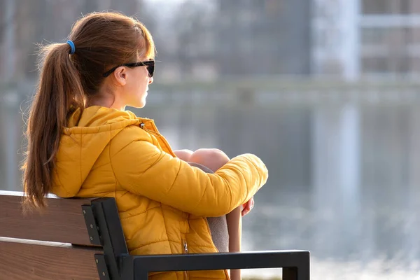 Jonge vrouw zit op parkbank ontspannen op warme lentedag — Stockfoto