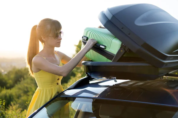 Mujer joven sacando la maleta verde del portaequipajes del coche. Concepto de viajes y vacaciones — Foto de Stock