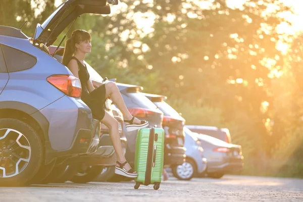 Mujer joven con maleta esperando al lado del coche. Concepto de viajes y vacaciones — Foto de Stock