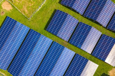 Temiz ekolojik elektrik enerjisi üretmek için sıra sıra güneş fotovoltaik panelleri olan sürdürülebilir büyük elektrik santralinin havadan görünüşü. Sıfır emisyon kavramı ile yenilenebilir elektrik