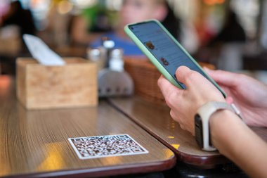 Konuk elin restoranda yemek sipariş ederken çevrimiçi menü için qr kodunu cep telefonuyla taraması
