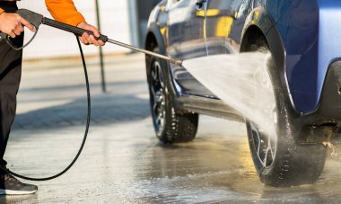 Erkek sürücünün otomobil yıkama servisinde yüksek basınçlı su jeti ile arabasını yıkaması.