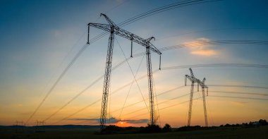 Gün batımında elektrik hatları olan yüksek voltaj kuleleri.