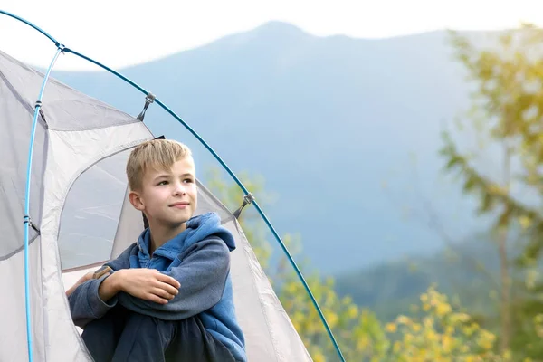 Мальчик-турист сидит в палатке в горном кемпинге и наслаждается видом на природу — стоковое фото