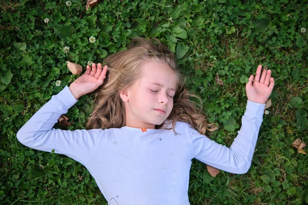 Портрет красивої дівчинки на відкритому повітрі лежить на газоні — стокове фото