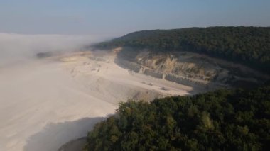 Kazı araçları ve çöp kamyonlarıyla inşaat endüstrisi için kireçtaşı malzemelerinin açık maden sahası görüntüsü