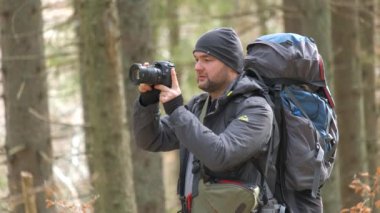 Sırt çantalı fotoğrafçı dijital fotoğraf makinesiyle doğanın fotoğraflarını çekiyor.