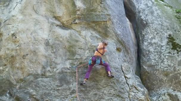 Wanita pendaki yang kuat memanjat dinding curam gunung berbatu. Wanita olahragawan melewati rute yang sulit. Terlibat dalam konsep hobi olahraga ekstrim — Stok Video