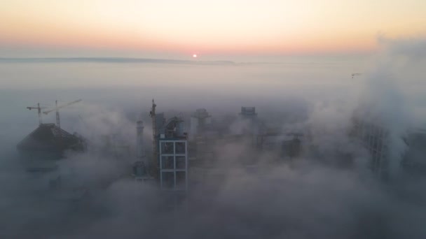 Vista aérea de la fábrica de cemento con estructura de planta de hormigón alto y grúa torre en el sitio de fabricación industrial en la noche brumosa. Producción y concepto de industria global — Vídeos de Stock