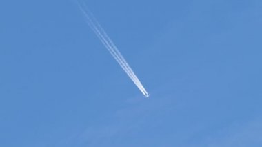 Mesafeli yolcu jet uçağı açık mavi gökyüzünde yüksek irtifada uçarken ardında beyaz duman izi bırakıyor. Hava taşımacılığı kavramı