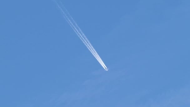 Avião de passageiros distantes voando em alta altitude no céu azul claro deixando vestígios de fumaça branca de contrail para trás. Conceito de transporte aéreo — Vídeo de Stock