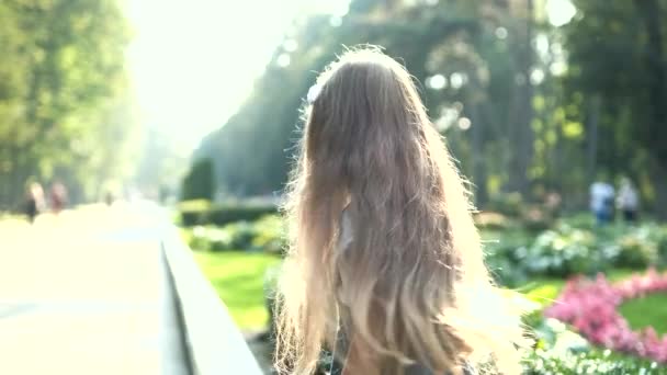 Malá hezká holčička s dlouhými vlasy chůze venku v zeleném letním parku na slunný den — Stock video