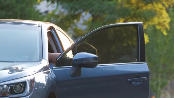 Young woman driver taking green suitcase out from her car walking down the street. Travelling and vacations concept — Stock Video