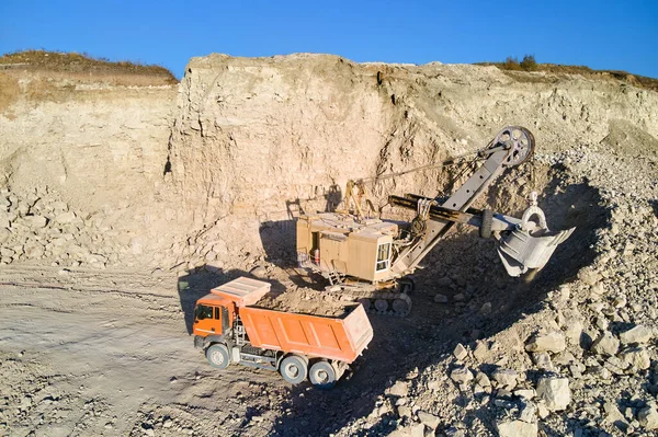 Αεροφωτογραφία ανοιχτού ορυχείου από ψαμμίτη υλικών για την κατασκευαστική βιομηχανία με εκσκαφέα να φορτώνει σκουπιδιάρικο με πέτρες. Βαρύς εξοπλισμός για εξόρυξη και παραγωγή χρήσιμων ορυκτών — Φωτογραφία Αρχείου