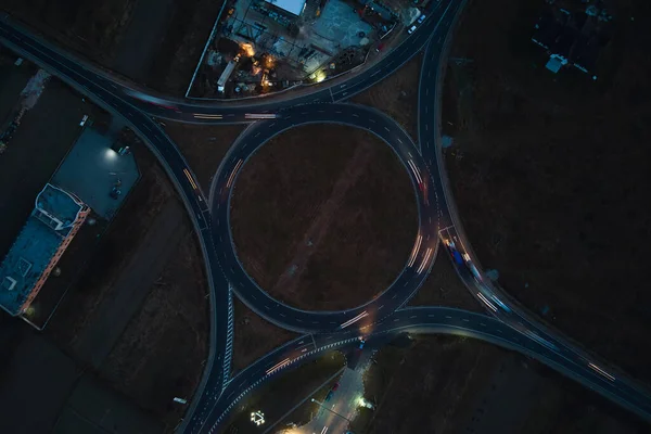 Luftaufnahme der Kreuzung eines Kreisverkehrs mit starkem Verkehr in der Nacht. Draufsicht auf Kreisverkehrskreuzungen in der Stadt. Rush Hour mit verschwommener Autofahrerampel — Stockfoto
