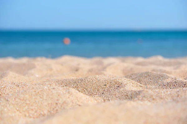 Primo piano di superficie di sabbia gialla pulita che copre la spiaggia sul mare con acqua di mare blu sullo sfondo. Concetto di viaggio e vacanze — Foto Stock