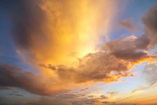 Paisagem amarela dramática do por do sol com nuvens inchadas iluminadas pelo sol de ajuste alaranjado e pelo céu azul — Fotografia de Stock