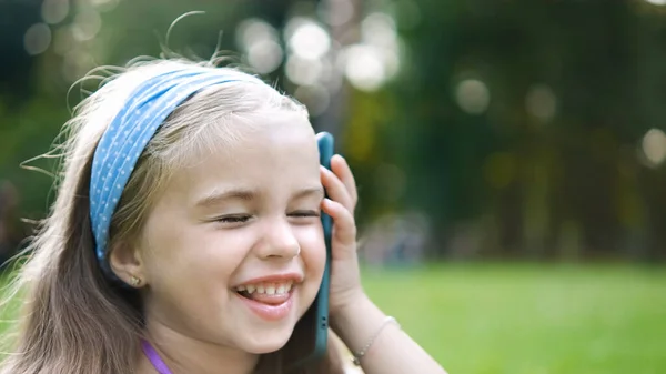 여름 공원에서 휴대폰으로 대화하고 있는 행복 한 어린 소녀 — 스톡 사진