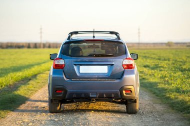 Çakıl yolunda mavi off-road arabalı manzara. Otomobille seyahat, vahşi yaşam macerası, keşif gezisi ya da bir SUV otomobili ile aşırı seyahat. Offroad 4x4 aracı gün doğumunda arazide olacak.