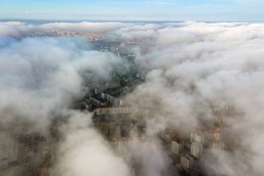 Modern şehrin üzerinde yüksek binaları olan kabarık beyaz bulutların üst hava manzarası
