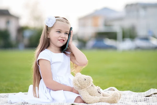 Söt liten barn flicka talar på mobiltelefon ler glatt utomhus på sommaren — Stockfoto