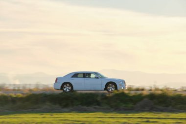 Gün batımında şehir içi yolda hızlı giden bir araba. Akşamları otoyol trafiği