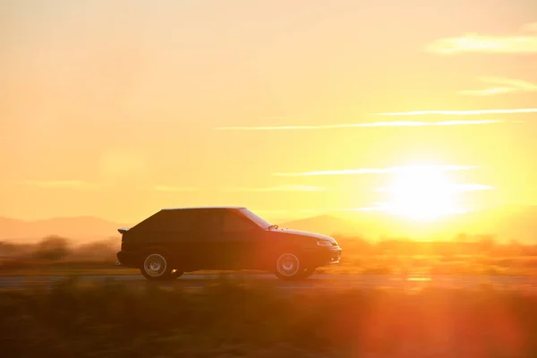 Coche que conduce rápido en la carretera interurbana al atardecer. Tráfico por carretera por la noche — Foto de Stock