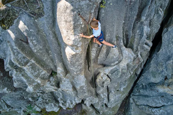Jonge jongen klimmend op een steile muur van rotsachtige bergen. Kid klimmer overwint uitdagende route. Betrokken bij het concept extreme sport — Stockfoto