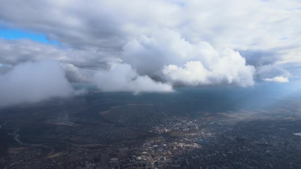 Flygfoto från flygplansfönstret på hög höjd över fjärran stad täckt med fluffiga cumulusmoln som bildas före regnstorm — Stockvideo