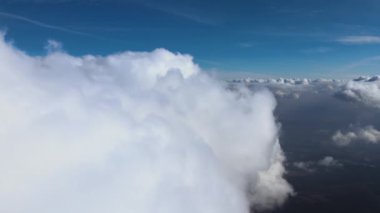 Dünya 'nın yüksek irtifasındaki uçak penceresinden hava manzarası beyaz kabarık kümülüs bulutlarıyla kaplı.