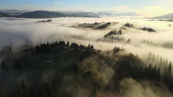 Вид с воздуха на сельские дома на вершине холма осенью туманные горы на восходе солнца — стоковое видео