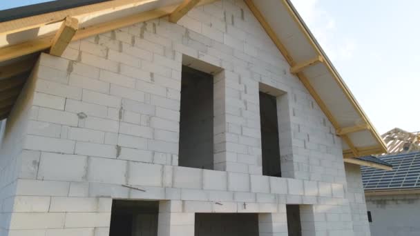 Vista aérea da casa inacabada com paredes de concreto leve aerado e estrutura de telhado de madeira coberta com telhas metálicas em construção — Vídeo de Stock
