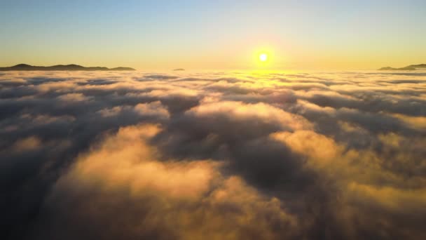 Aerial view of colorful sunrise over white dense fog with distant dark silhouettes of mountain hills on horizon — Stock Video