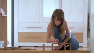 Yaratıcı kız, yüksek bina yapısındaki tahta blokları istifleyerek oyun oynuyor. El hareketi kontrolü ve konsantrasyon becerileri kavramı
