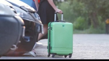 Genç bayan sürücü bagajını arabasına koyuyor. Seyahat ve tatil kavramı