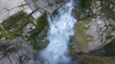 Yazın yağmur ormanlarında kayalık kayalıklardan dökülen beyaz köpüklü suyla dağ nehrindeki muhteşem şelale manzarası.