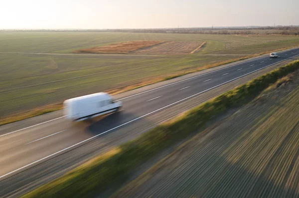 Воздушный вид размытого быстро движущегося грузового фургона, движущегося по шоссе, перевозящего товары. Концепция транспортировки и логистики — стоковое фото