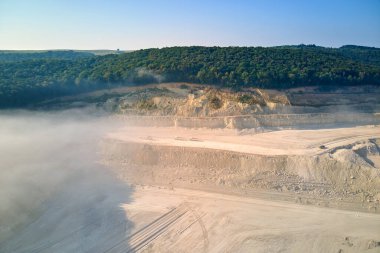 Kazı araçları ve çöp kamyonlarıyla inşaat endüstrisi için kireçtaşı malzemelerinin açık maden sahası görüntüsü
