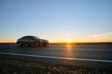 Gün batımında şehir içi yolda hızlı giden bir araba. Akşamları otoyol trafiği