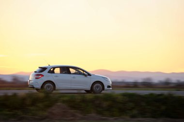 Gün batımında şehir içi yolda hızlı giden bir araba. Akşamları otoyol trafiği