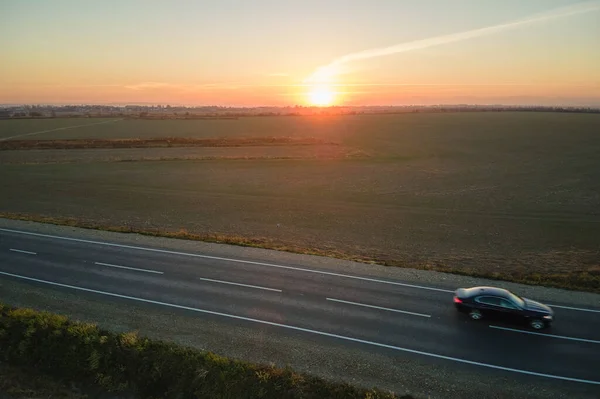 Вид с воздуха на междугороднюю дорогу с размытыми быстро движущейся окружающей среды дружественный электрический автомобиль на закате. Вид сверху с дрона дорожного движения в вечернее время — стоковое фото