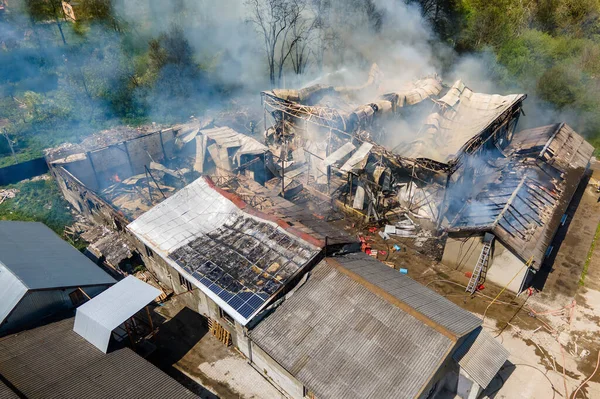 Вид с воздуха на разрушенное здание с разрушенной крышей и поднимающимся темным дымом — стоковое фото
