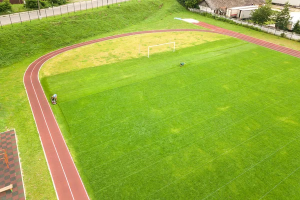 Вид з повітря на спортивний стадіон з червоними біговими доріжками і зеленим трав'яним футбольним полем — стокове фото