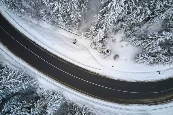 Вид с воздуха на зимний пейзаж с заснеженными горными лесами и извилистыми лесами — стоковое фото