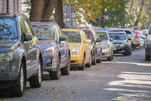 Stadstrafik med många bilar parkerade i linje på gatan sida — Stockfoto