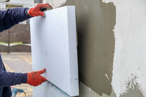 Robotnik budowlany montujący blachy styropianowe na ściance fasady domu w celu ochrony termicznej — Zdjęcie stockowe