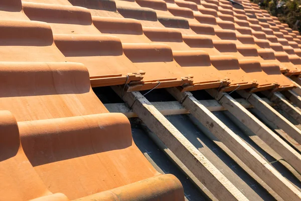 Linhas sobrepostas de telhas de cerâmica amarela montadas em tábuas de madeira cobrindo telhado de edifício residencial em construção — Fotografia de Stock