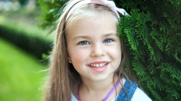 여름 공원에서 카메라 앞에 서 있는 행복하고 예쁜 여자 아이의 모습 — 스톡 사진
