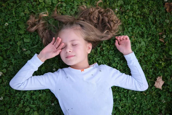 Porträtt av söt barn flicka utomhus liggande på gräsmattan — Stockfoto